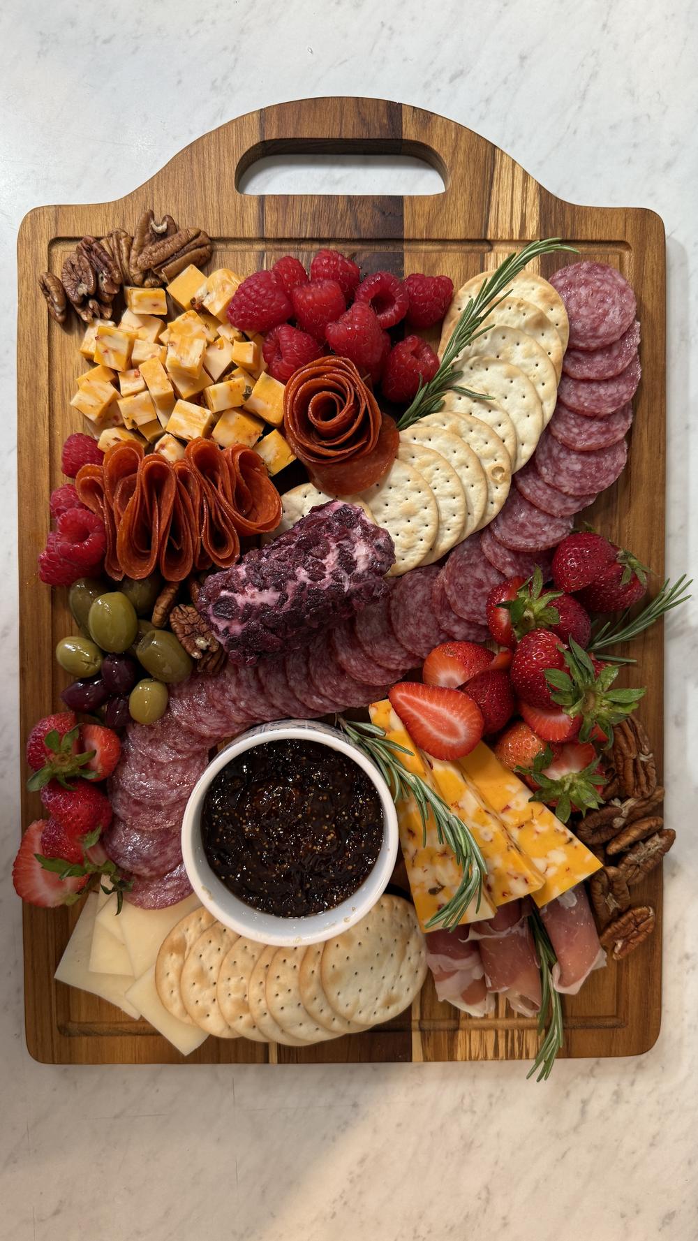 Overhead view of a signature Miora Cheese board with salami rose, berries, cheeses and crackers