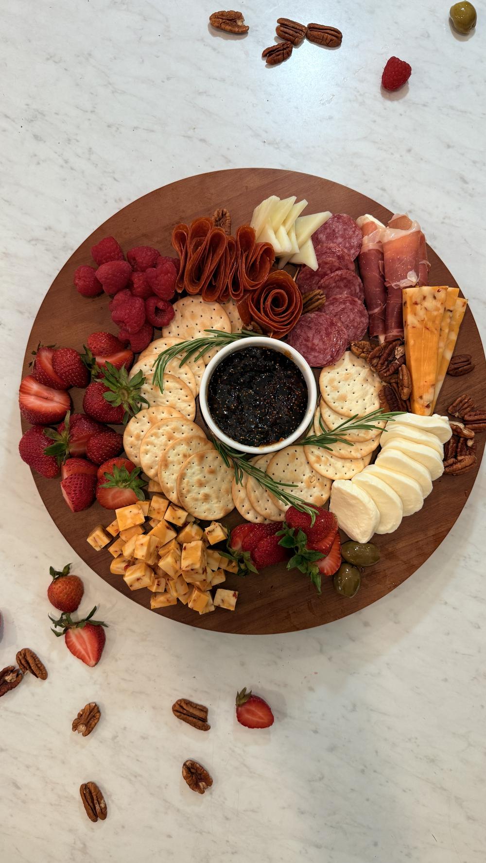 Round cheese board with berries, cheeses, crackers and a caviar-style centerpiece