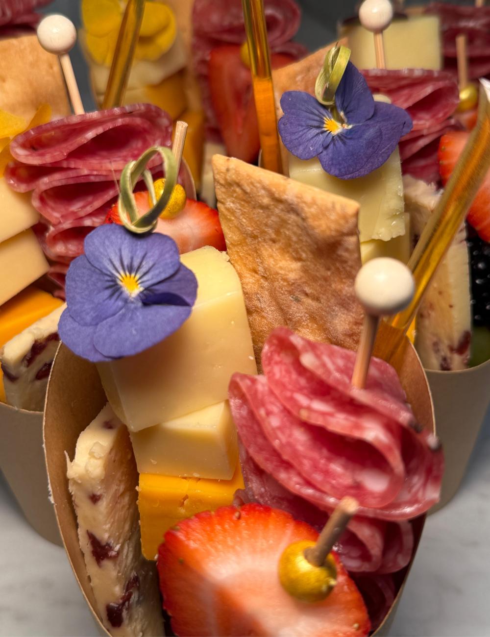 Close-up of a charcuterie cup with salami rose, cheese and edible flower