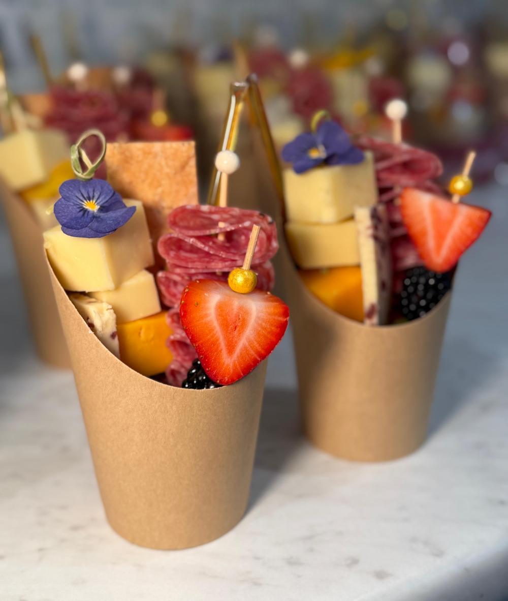 Individual charcuterie cups with cheese, salami roses, strawberries and edible flowers
