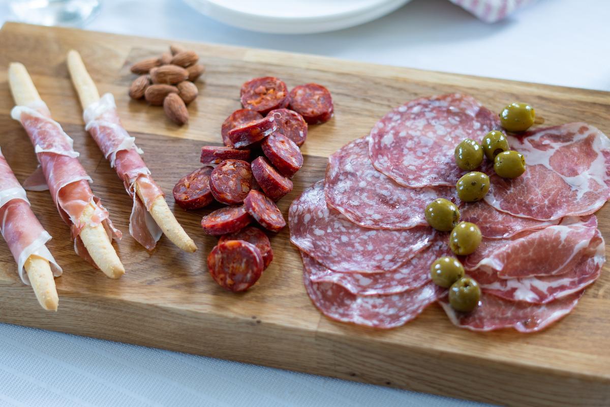 Cured meat selection with salami, olives, almonds and grissini on a wooden board